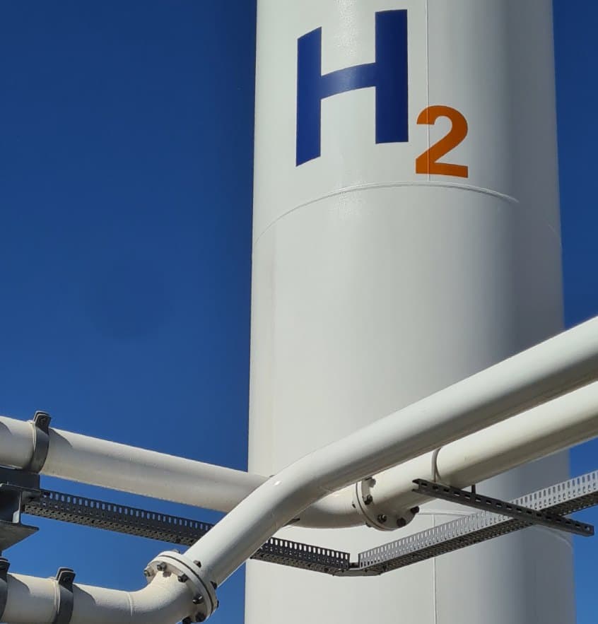 White hydrogen storage tank marked H2 against a blue sky